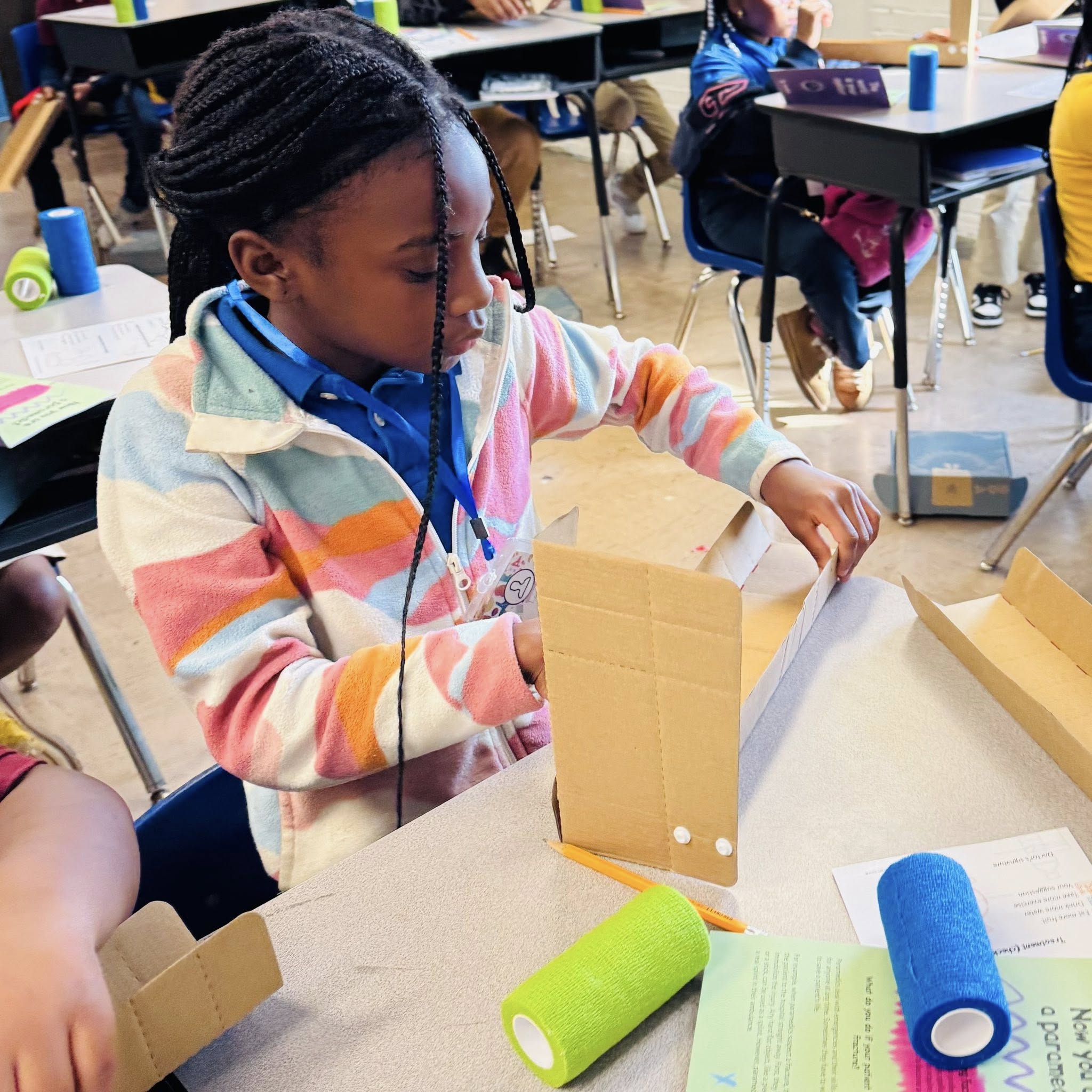 A girl folding cardboard pieces.